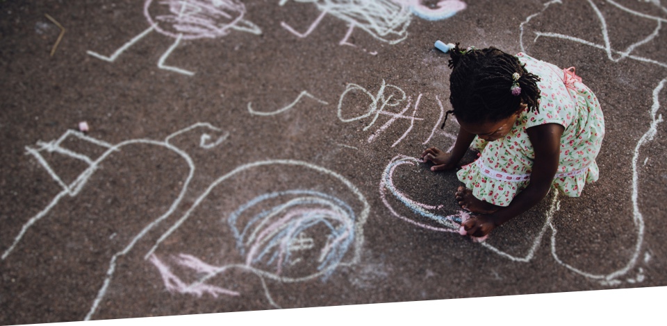 Young girl drawing in chalk on the sidewalk.