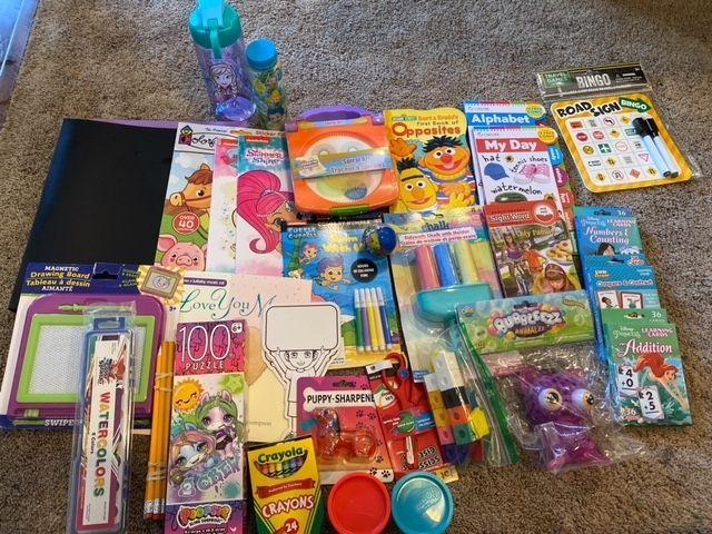 Pile of coloring and school materials on carpet.