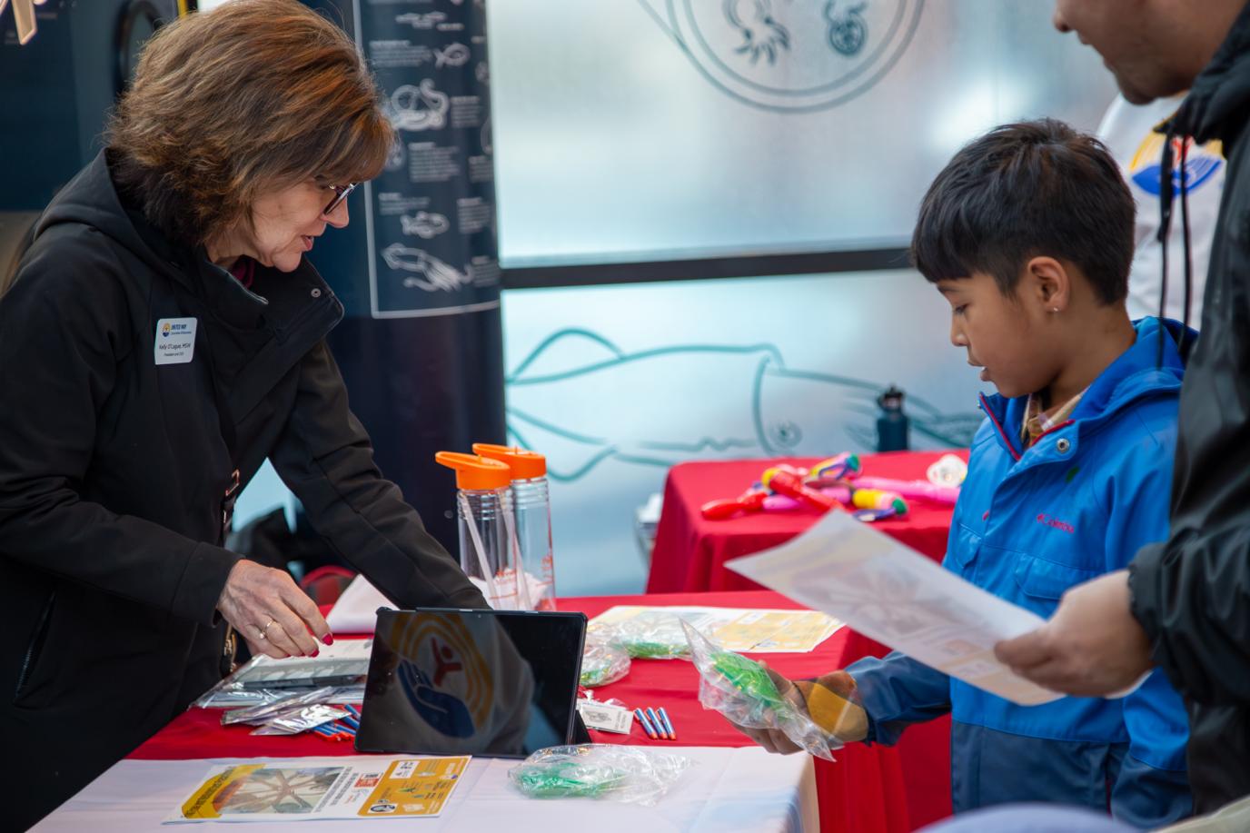 Kelly sharing information with a child at PSM booth at OMSI