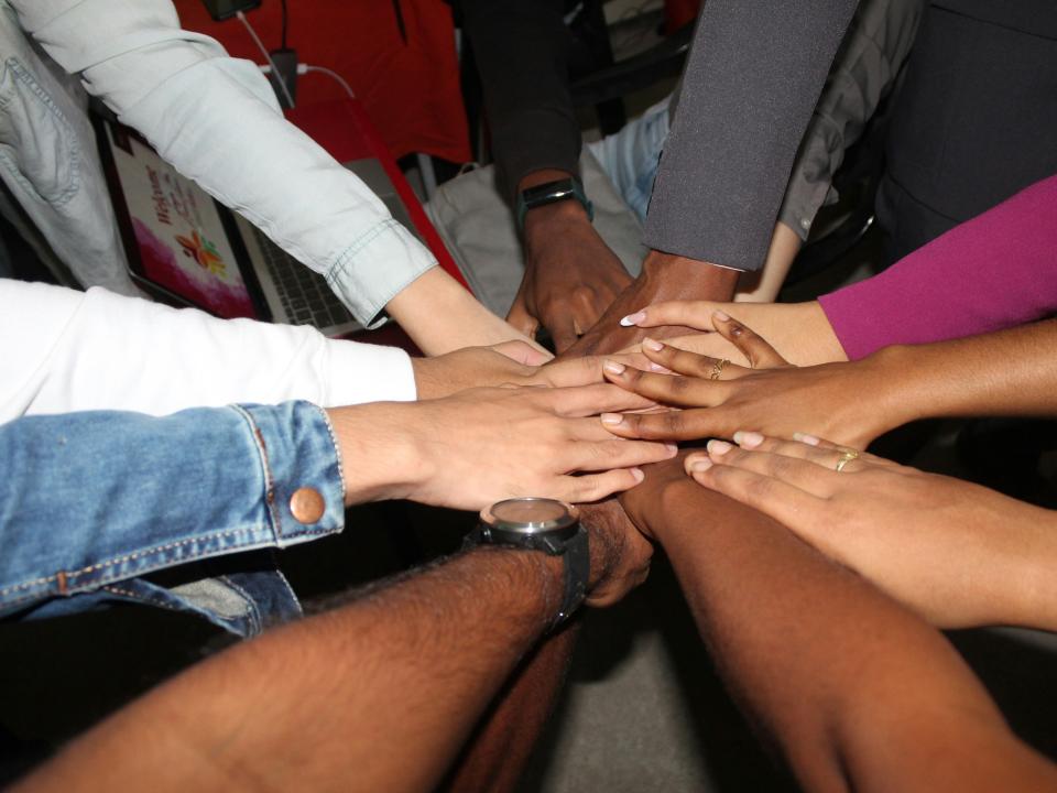 Group of hands in, as in a huddle. Rinesh Kumar Ghirao, Unsplash