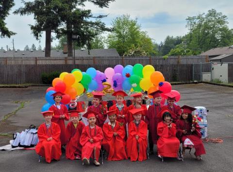 group photo of preschoolers in red graduation gowns