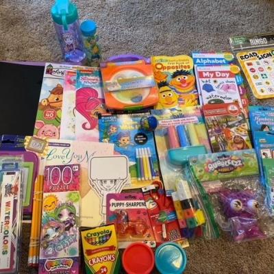 pile of coloring books and school materials on carpet.